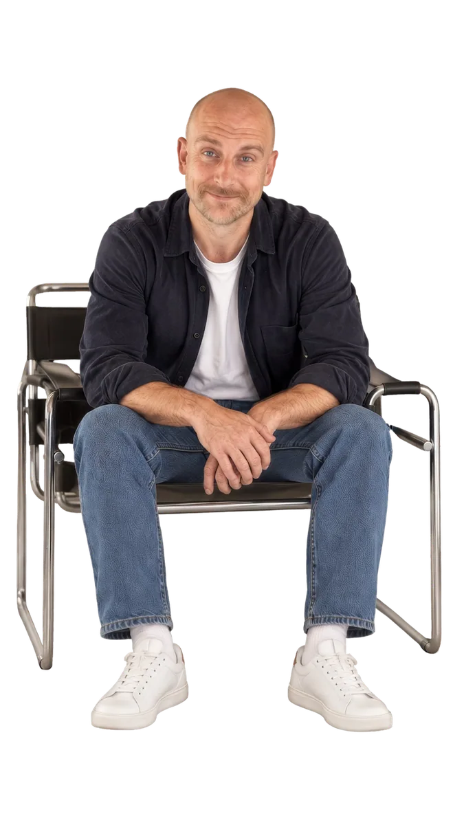 Nate, smiling, sitting forward in a chrome and leather chair.
